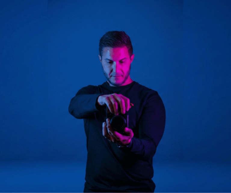 nu media videographer adjusting a camera in a blue studio with pink accent lighting