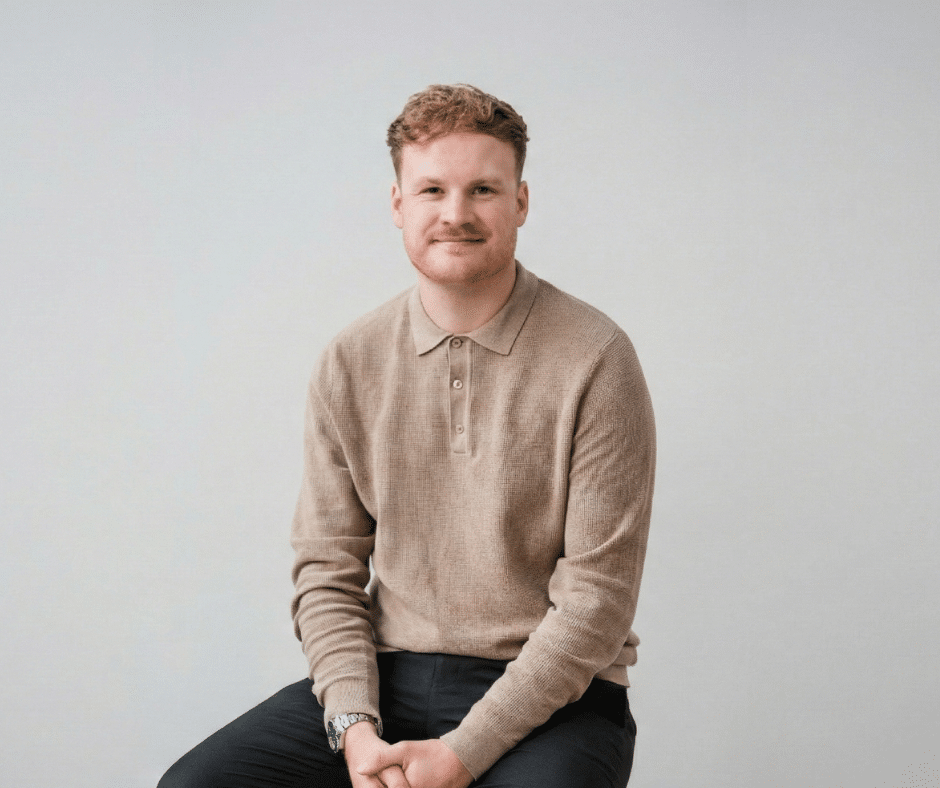 nu media team member portrait in a neutral studio, seated and smiling for a professional headshot