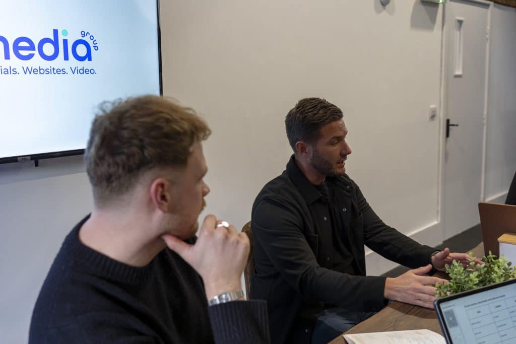 Team meeting at nu media group discussing a micro content package around a boardroom table beside a presentation screen.