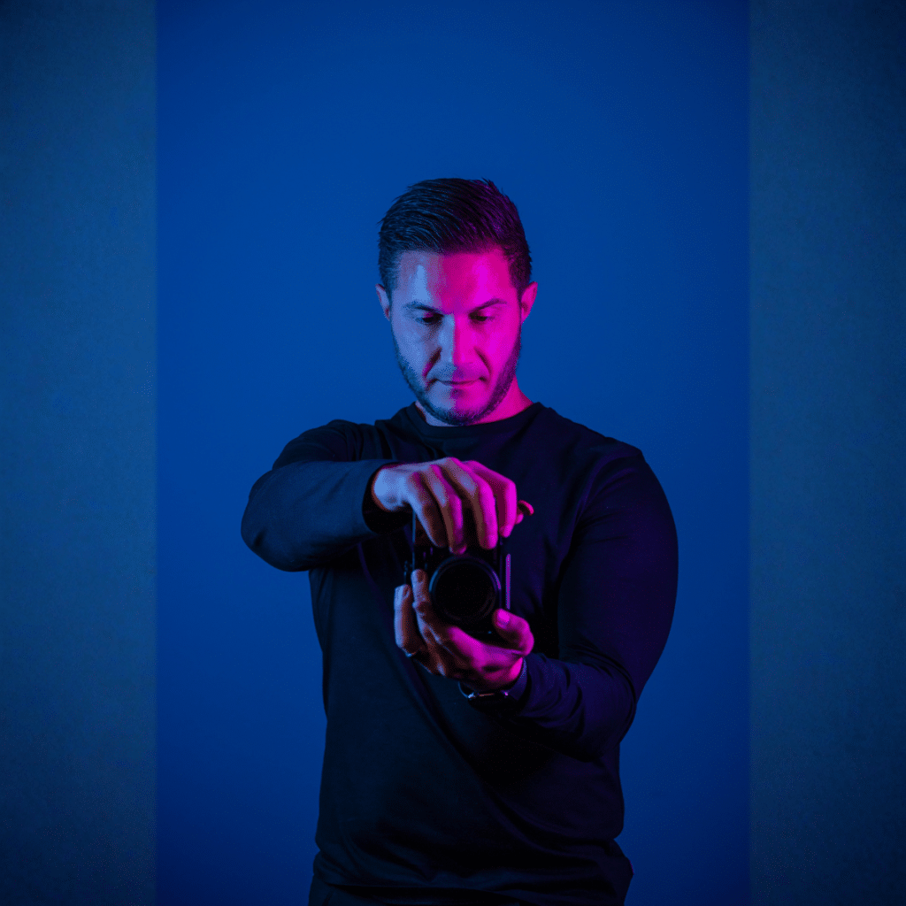 Aaron, professional photographer for business at nu media group, adjusting camera lens under studio lighting
