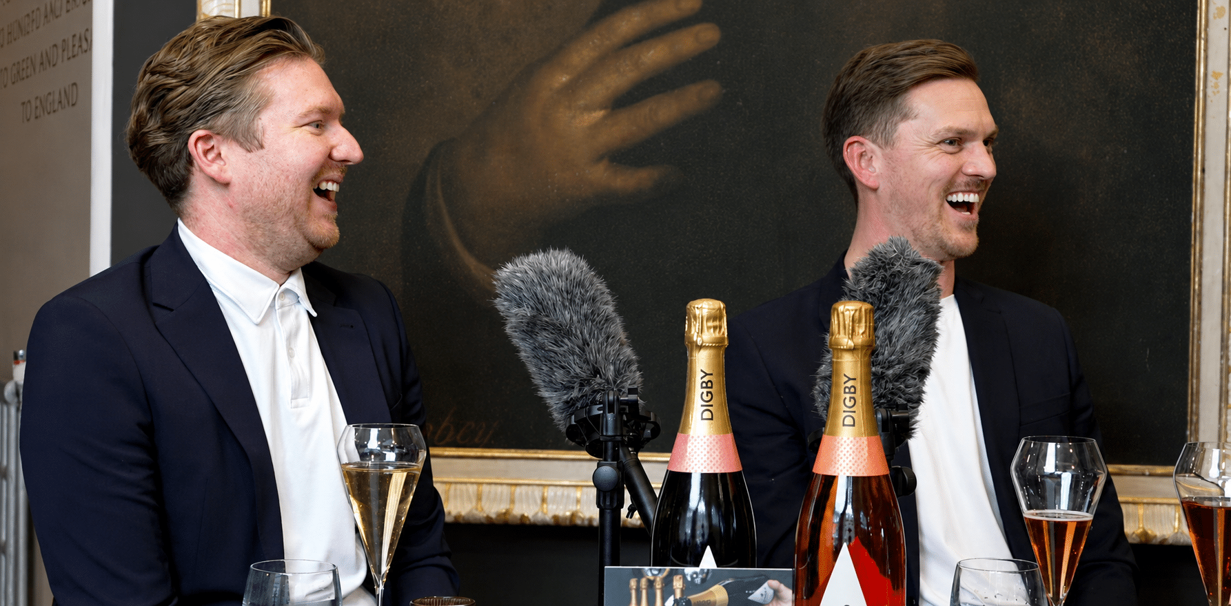 Two LHB Estate Agents hosts laughing during podcast filming session with microphones and Digby champagne
