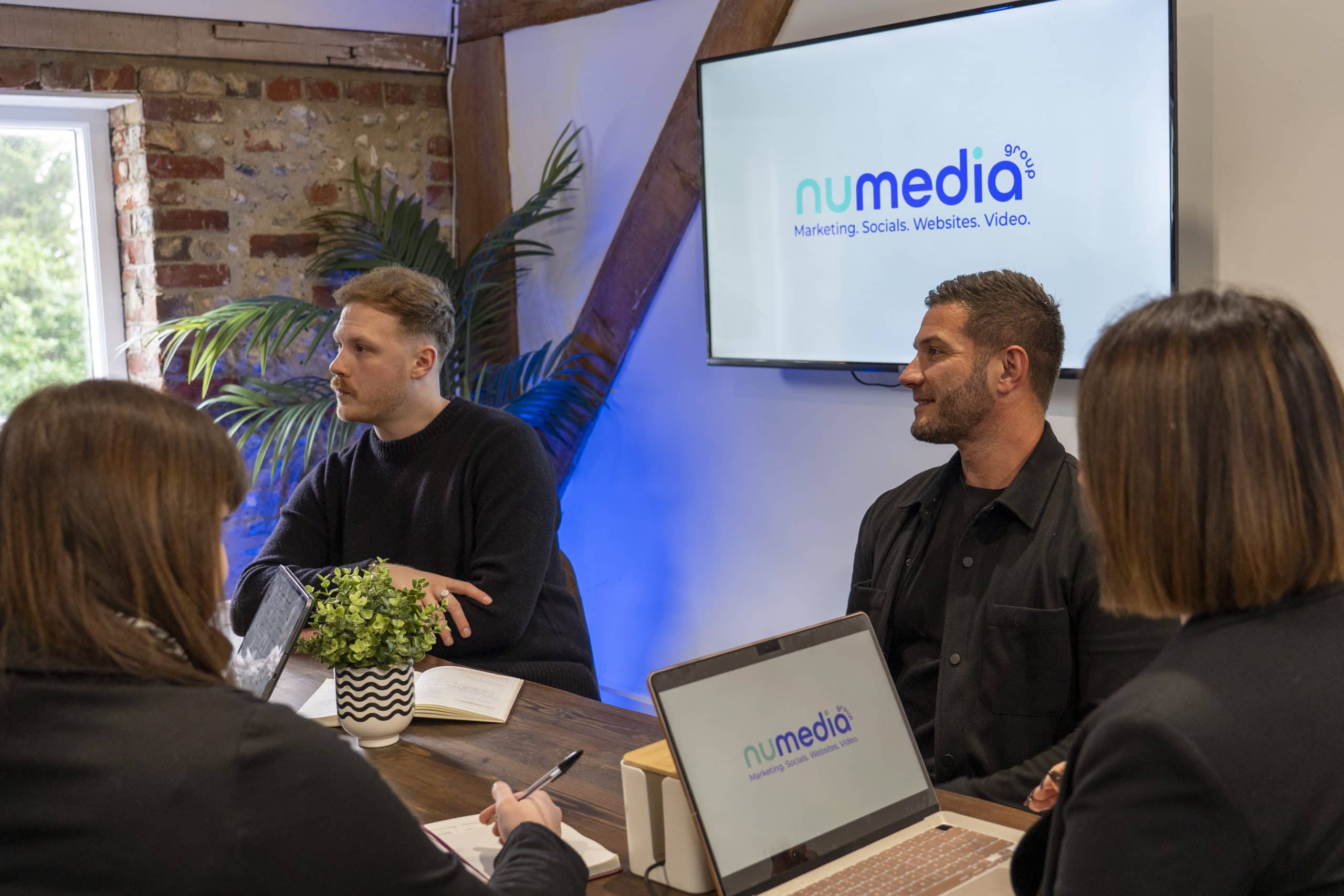 nu media group team in client meeting with branded screen and laptops in West Sussex studio